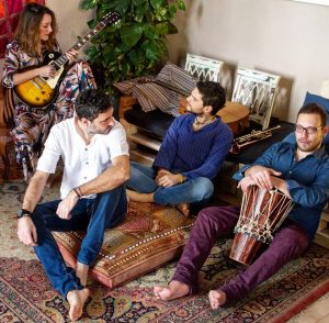 alt="foto della band seduta con gli strumenti"/